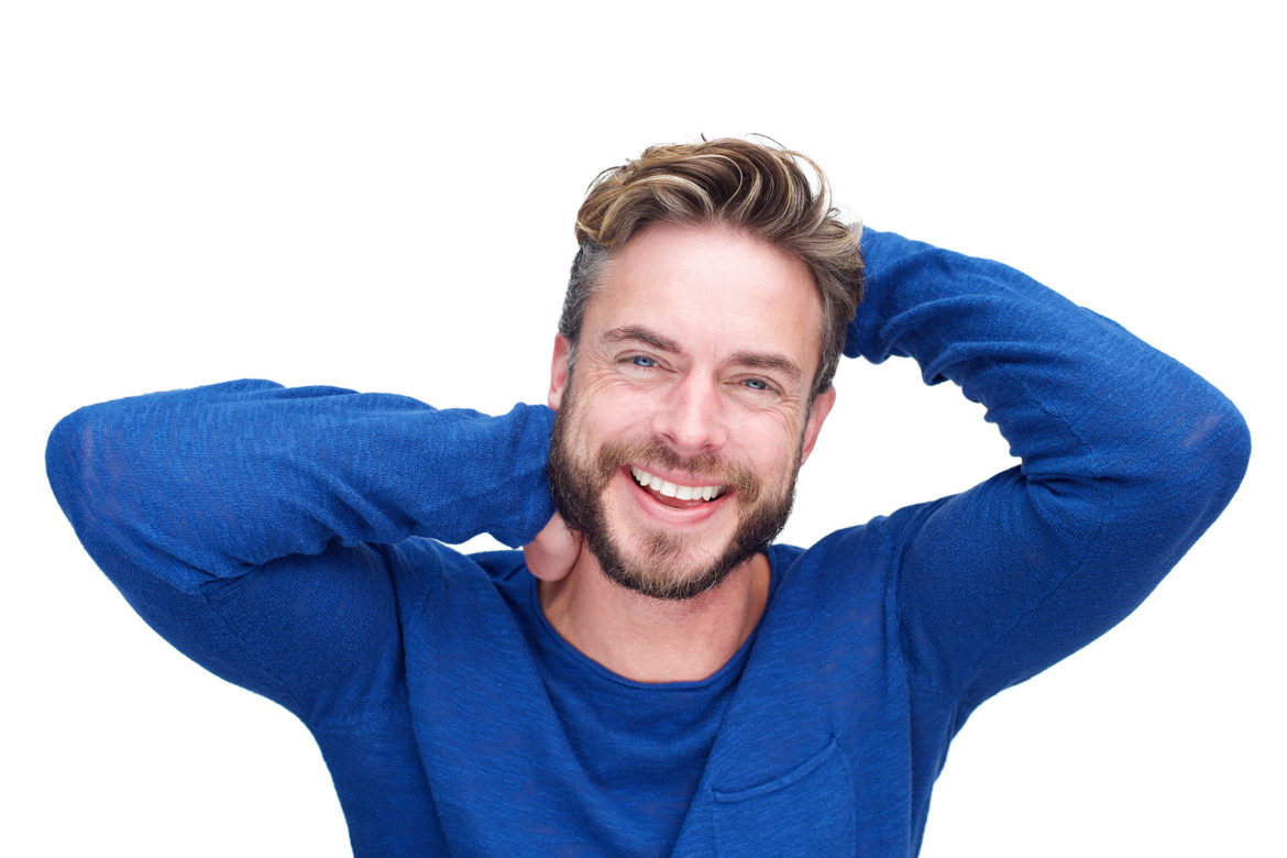 Close up portrait of a handsome man with beard laughing with hands in hair